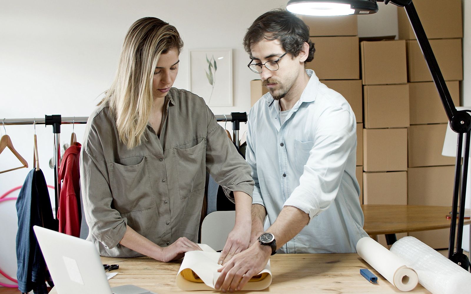 Two people wrapping a product for shipping at a packing table